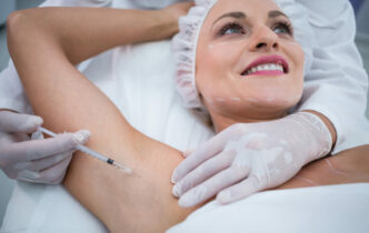 Close-up of doctor injecting woman on her arm pits